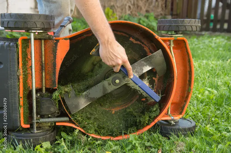 close-up of a lawn mower repair technician examining a mower’s carburetor in workshop