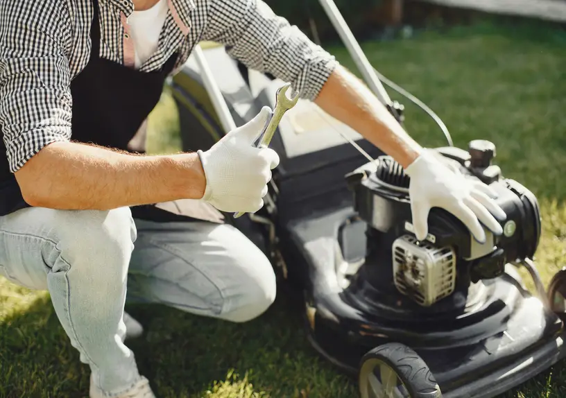 Man repairs lawnmover in a backyard